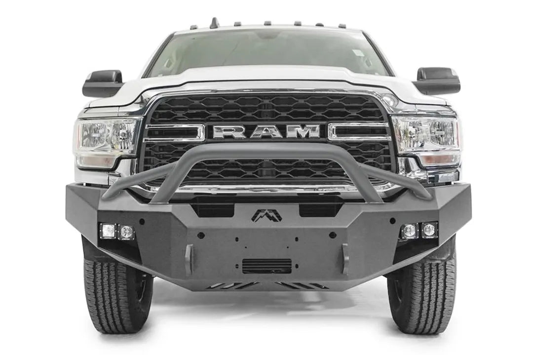 Fab Fours Premium winch bumper with pre-runner guard on a white Ram 2500, straight-on front view, showing the pre-runner hoop, winch fairlead opening and cube lights