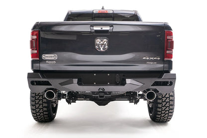 Fab Fours Vengeance rear bumper on a lifted dark gray Ram 1500, straight rear view, with honeycomb mesh light openings, center license plate area, hitch receiver, and dual exhaust tips