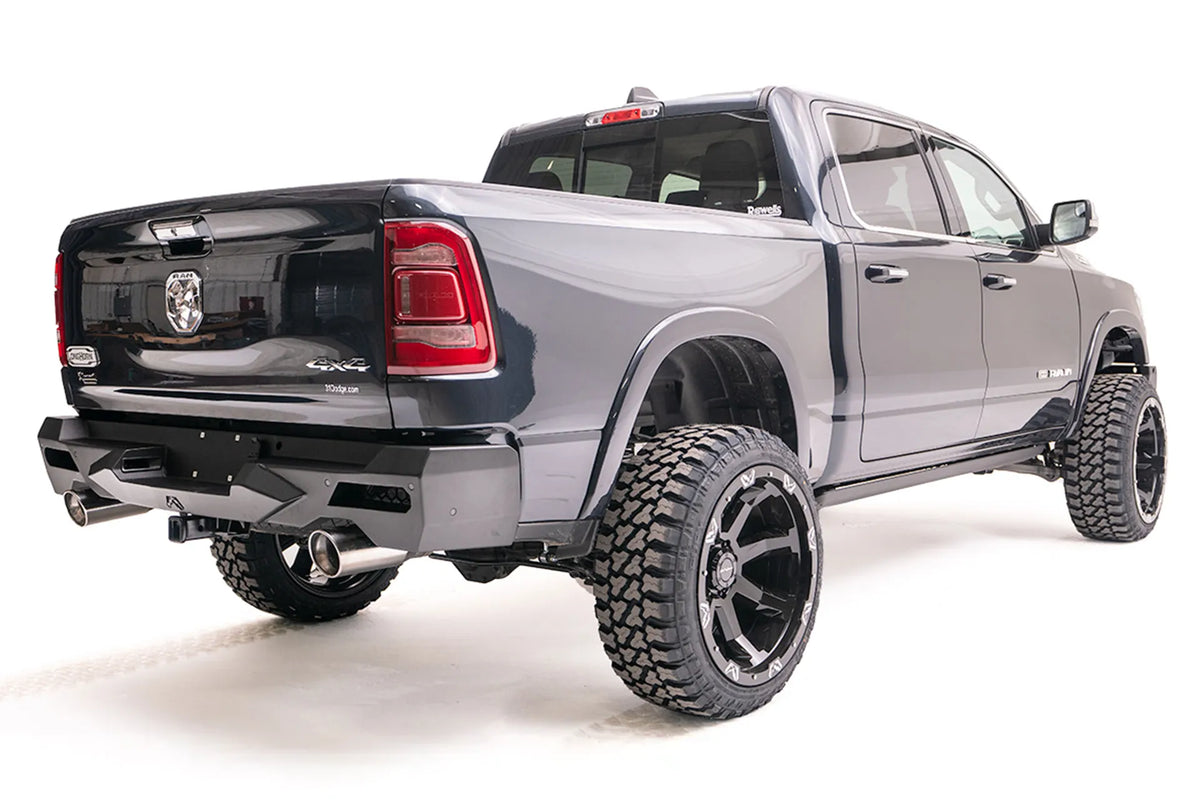 Fab Fours Vengeance rear bumper on a lifted dark gray Ram 1500, passenger-side rear three-quarter view, with hitch receiver and dual exhaust tips