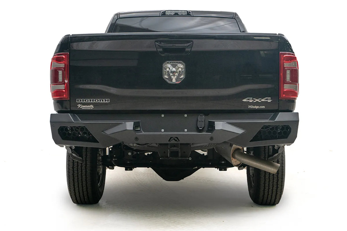 Fab Fours Vengeance rear bumper on a black Ram 2500, straight rear view, with honeycomb mesh light openings, center license plate area, and hitch receiver