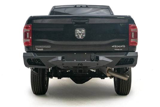 Fab Fours Vengeance rear bumper on a black Ram 2500, straight rear view, with honeycomb mesh light openings, center license plate area, and hitch receiver