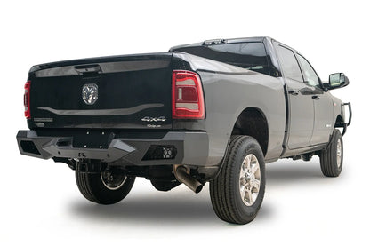 Fab Fours Vengeance rear bumper with honeycomb mesh light openings on a black Ram 2500, passenger-side rear three-quarter view, with hitch receiver