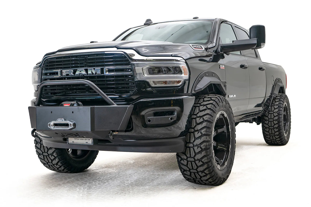 Fab Fours winch mount on a black lifted Ram 2500, front driver-side three-quarter view, showing the winch plate, mounted winch and tube hoop