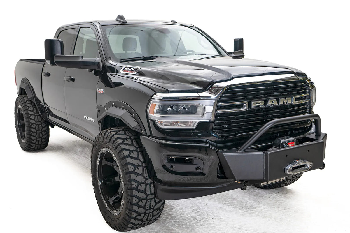 Fab Fours winch mount on a black lifted Ram 2500, front passenger-side three-quarter view, showing the winch plate, mounted winch and tube hoop