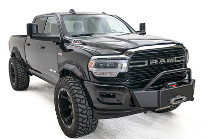 Fab Fours winch mount on a black lifted Ram 2500, front passenger-side three-quarter view, showing the winch plate, mounted winch and tube hoop