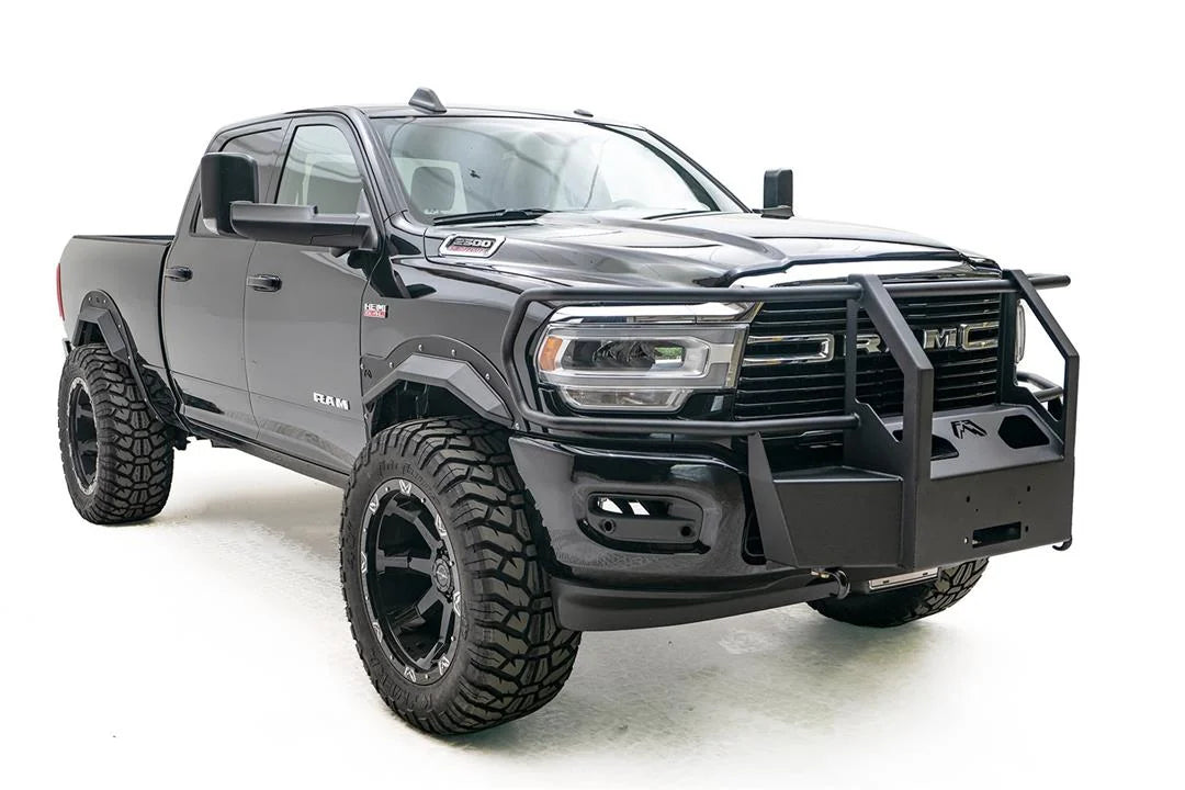 Fab Fours winch mount with full guard on a black lifted Ram 2500, front passenger-side three-quarter view, showing the full guard uprights, side bars and winch plate