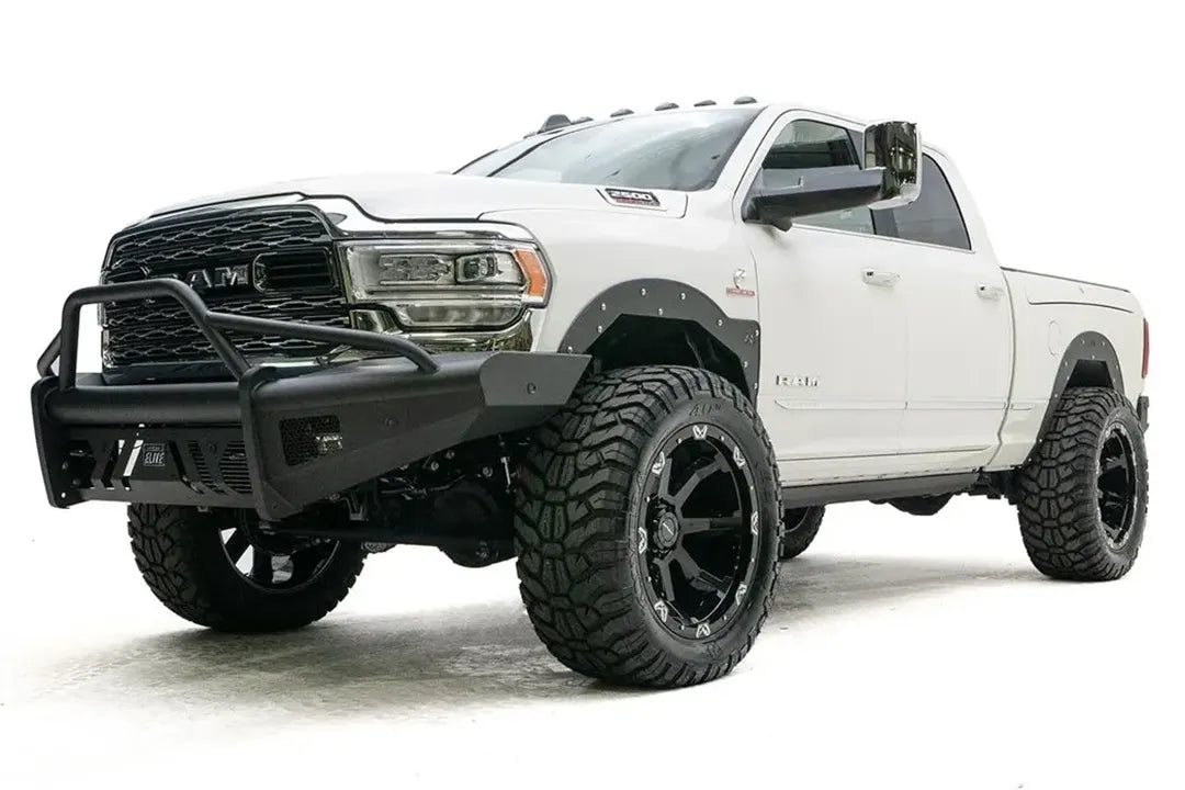 Fab Fours Black Steel Elite front bumper with pre-runner guard on a white lifted Ram 2500, front driver-side three-quarter view, showing the pre-runner hoop, wrap-around wings and skid plate