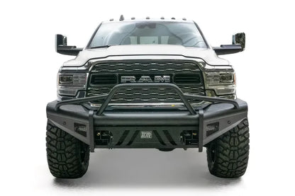 Fab Fours Black Steel Elite front bumper with pre-runner guard on a white lifted Ram 2500, straight-on front view, showing the pre-runner hoop, Elite badge and slotted skid plate