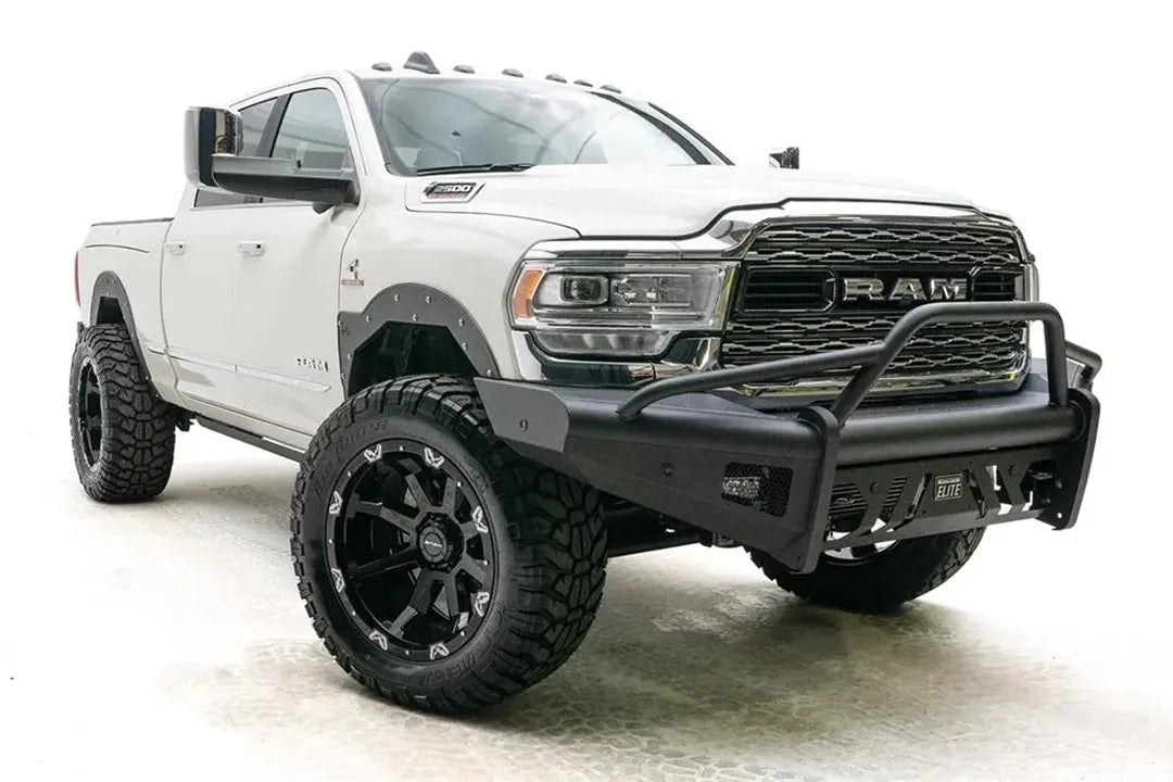 Fab Fours Black Steel Elite front bumper with pre-runner guard on a white lifted Ram 2500, front passenger-side three-quarter view, showing the pre-runner hoop, side wraps and skid plate