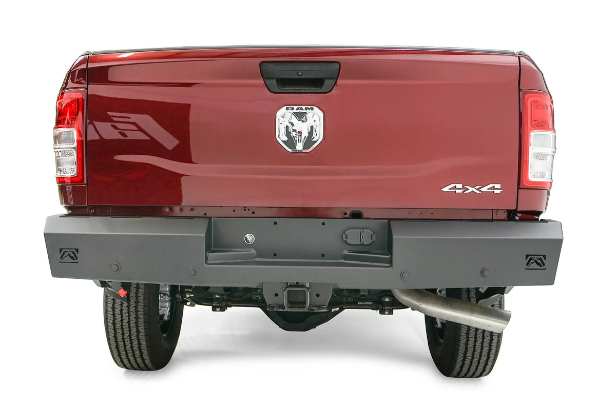 Fab Fours Red Steel rear bumper on a dark red Ram 2500, straight-on rear view, showing the recessed plate pocket, logo end cutouts and receiver hitch access