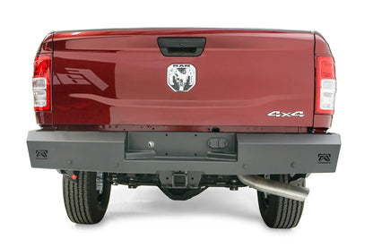Fab Fours Red Steel rear bumper on a dark red Ram 2500, straight-on rear view, showing the recessed plate pocket, logo end cutouts and receiver hitch access
