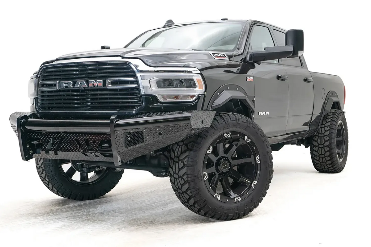 Fab Fours Black Steel front bumper on a black lifted Ram 2500, front driver-side three-quarter view, showing the diamond-plate wings, center tube and mesh light openings