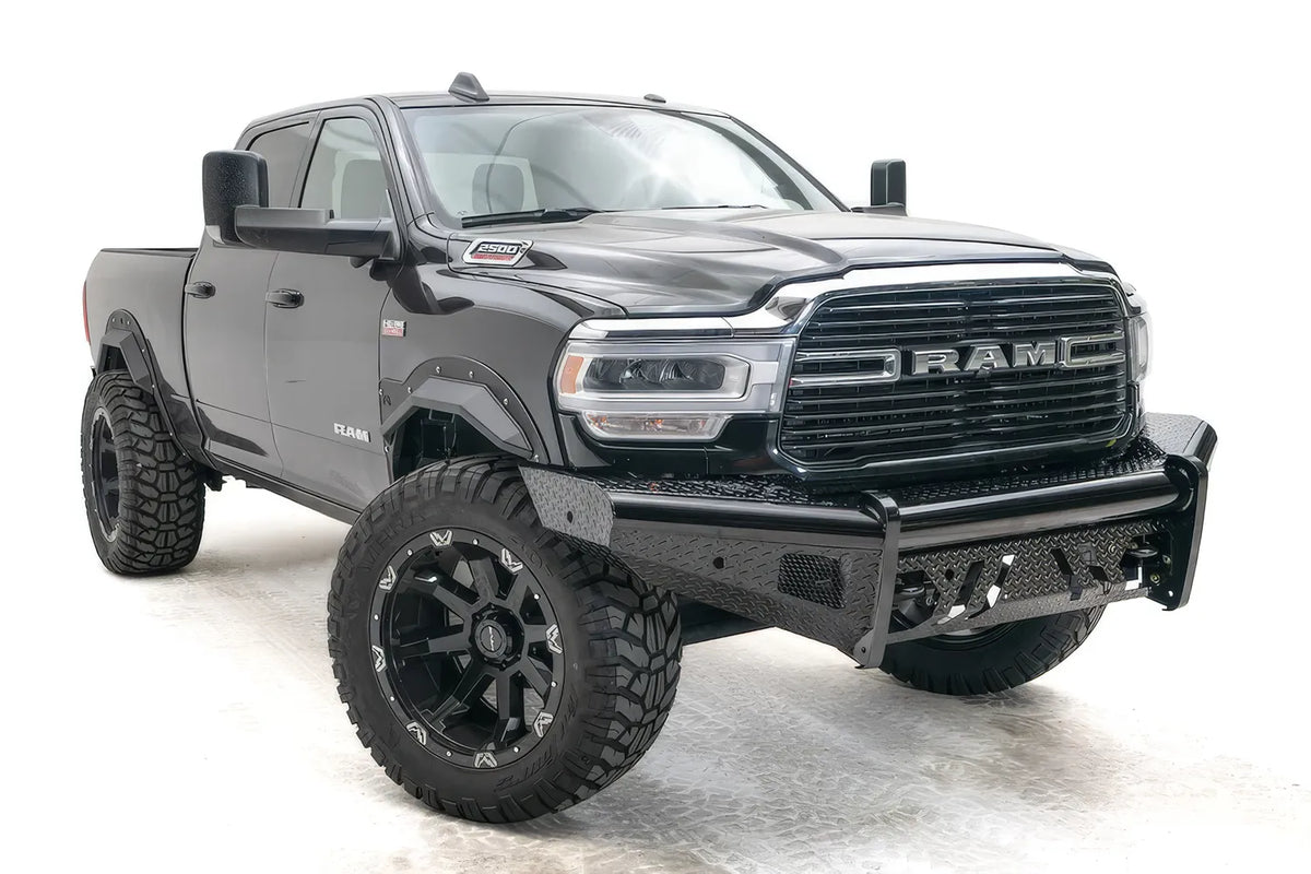Fab Fours Black Steel front bumper on a black lifted Ram 2500, front passenger-side three-quarter view, showing the diamond-plate face, center tube and angled wings