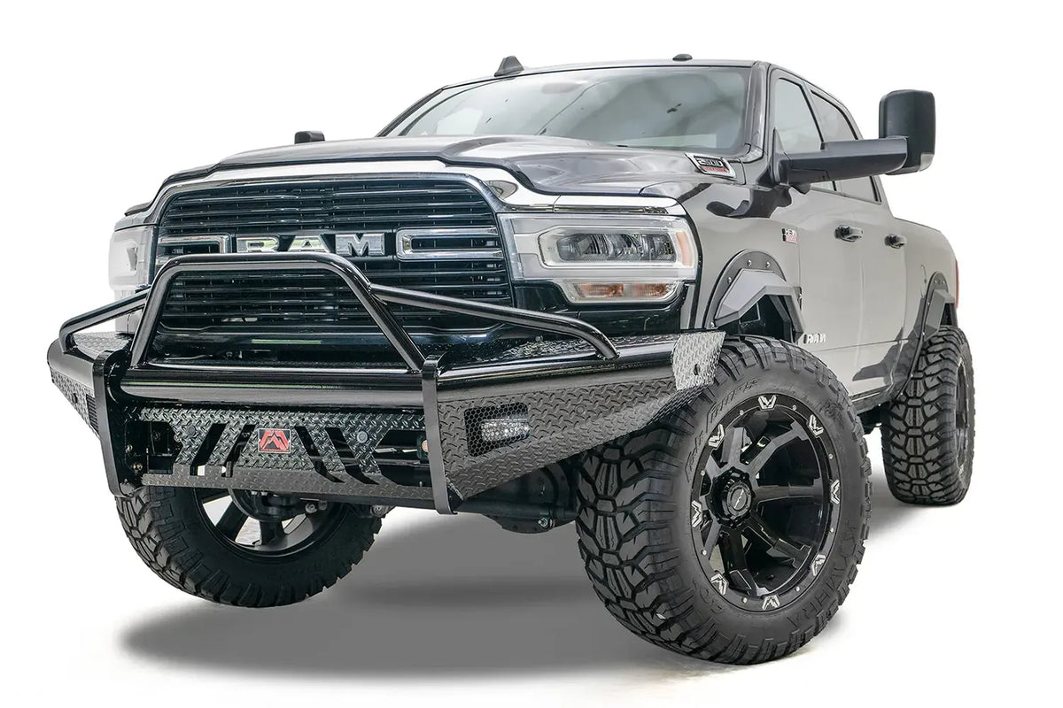Fab Fours Black Steel front bumper with pre-runner guard on a black lifted Ram 2500, front driver-side three-quarter view, showing the pre-runner hoop, diamond-plate wings and red logo badge
