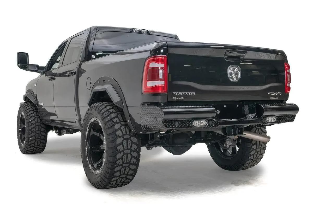 Fab Fours Black Steel rear bumper with diamond plate corner on a lifted black Ram 2500, rear three-quarter view