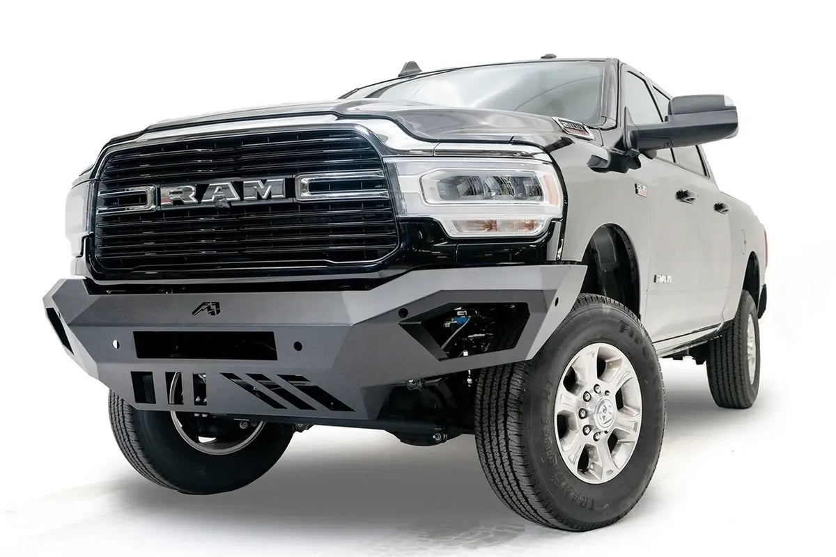 Fab Fours Vengeance front bumper on a black Ram 2500, front driver-side three-quarter view, showing the angled wings, light bar opening and slotted skid plate