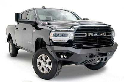 Fab Fours Vengeance front bumper on a black Ram 2500, front passenger-side three-quarter view, showing the angled wings, center logo and slotted skid plate