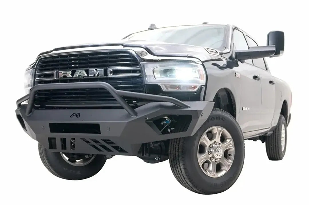 Fab Fours Vengeance front bumper with pre-runner guard on a black Ram 2500, front driver-side three-quarter view, showing the pre-runner hoop, angled wings and skid plate