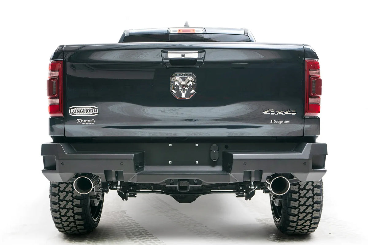 Fab Fours Premium rear bumper on a dark gray lifted Ram 1500, straight-on rear view, showing the dual exhaust cutouts, center plate area and receiver hitch access
