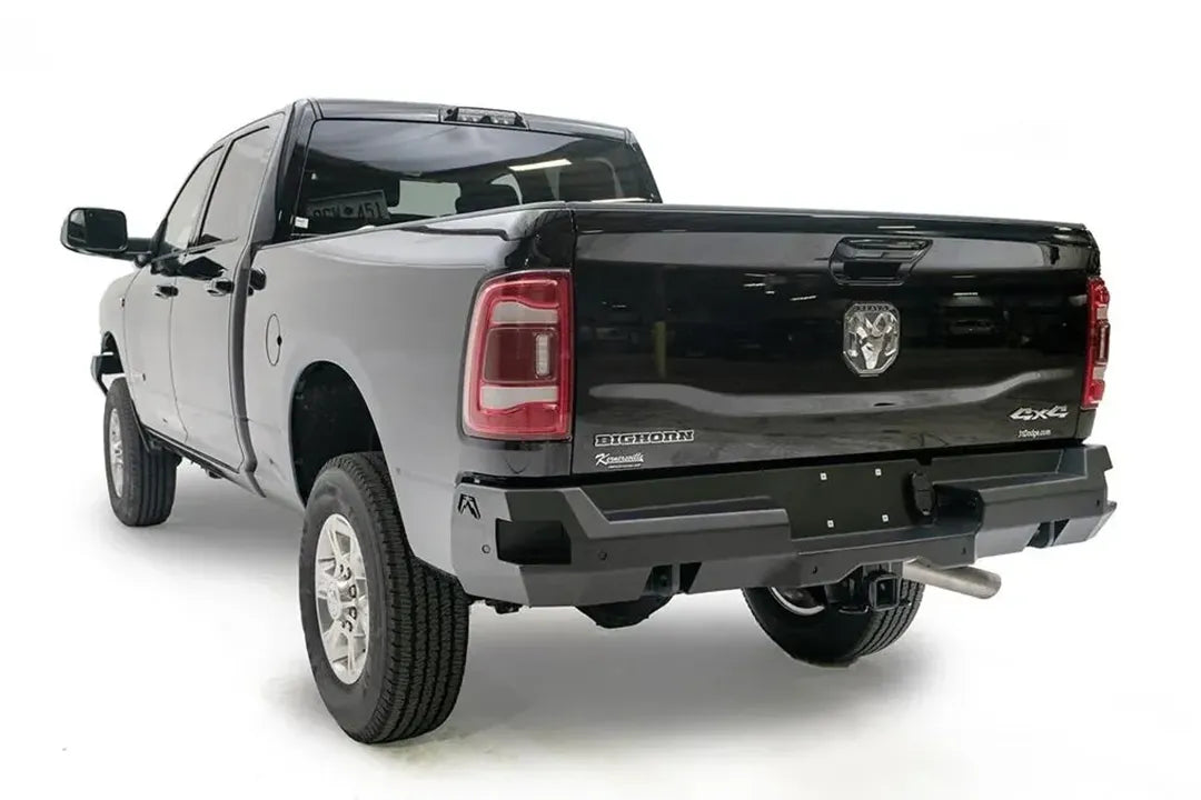 Fab Fours Premium rear bumper on a black Ram 2500, rear driver-side three-quarter view, showing the wrap-around end, sensor ports and plate area