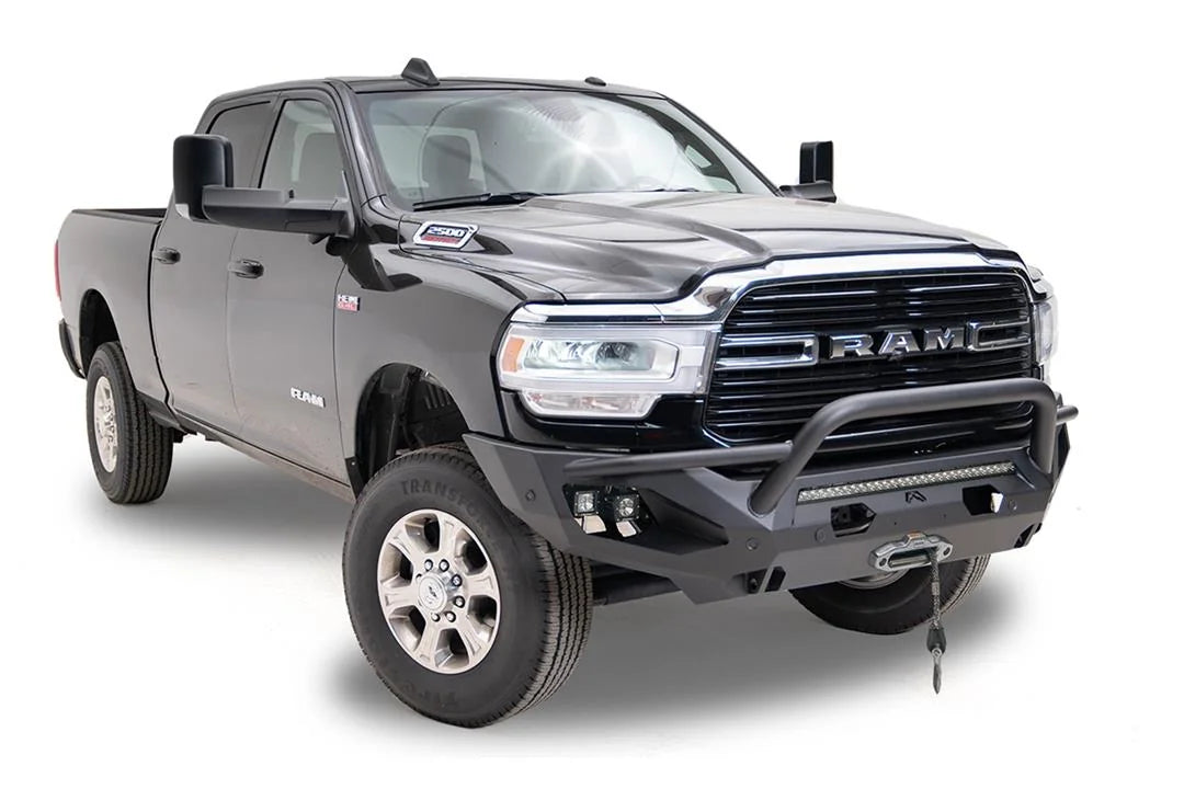 Fab Fours Matrix front bumper with pre-runner guard on a black Ram 2500, front passenger-side three-quarter view, showing the pre-runner hoop, light bar and cube lights