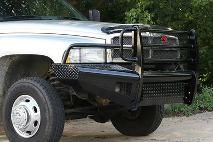 Fab Fours Black Steel front ranch bumper with full guard on a silver Ram 2500, front passenger-side three-quarter view outdoors, showing the full grille guard hoops, diamond-plate bumper face and integrated light openings