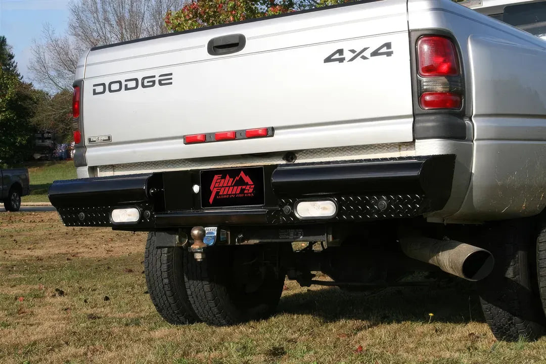 Fab Fours Black Steel Ranch rear bumper on a silver Dodge Ram dually parked on grass, low rear view