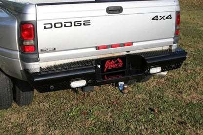 Fab Fours Black Steel Ranch rear bumper with diamond plate on a silver Dodge Ram dually parked on grass, rear three-quarter view