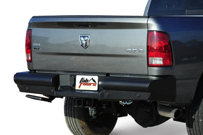 Fab Fours Black Steel Elite rear bumper on a gray Ram 2500, close-up rear view on a white background, showing the smooth bumper face, center plate pocket and hitch receiver