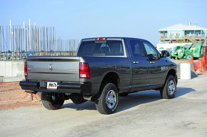 Fab Fours Black Steel Elite rear bumper on a gray Ram 2500, rear passenger-side three-quarter view outdoors, showing the smooth rear bumper, center plate pocket and hitch receiver