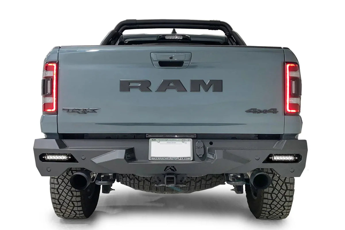 Fab Fours Vengeance rear bumper on a gray Ram 1500 TRX, straight rear view, with LED light bars installed in the corner openings, center license plate mount, and hitch receiver