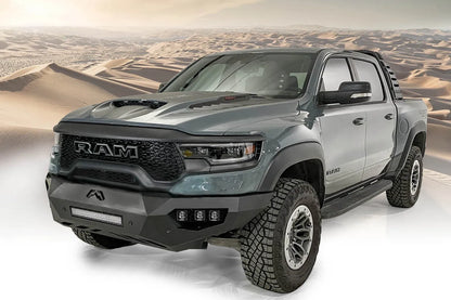 Fab Fours Vengeance front bumper on a gray Ram 1500 TRX, front driver-side three-quarter view against a desert backdrop, showing the low-profile bumper, light bar and wraparound end caps