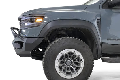 Fab Fours Vengeance front bumper with pre-runner guard on a gray Ram 1500 TRX, close-up of the driver-side bumper corner, showing the pre-runner tube, end cap and wheel clearance