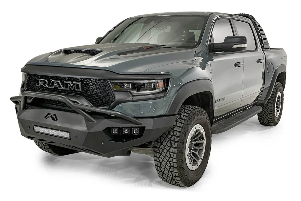 Fab Fours Vengeance front bumper with pre-runner guard on a gray Ram 1500 TRX, front driver-side three-quarter studio view, showing the pre-runner hoop, light bar and angular end caps
