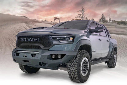 Fab Fours Matrix front bumper on a gray Ram 1500 TRX, front driver-side three-quarter view against a dune backdrop, showing the full-width bumper, top light bar and cube light pods