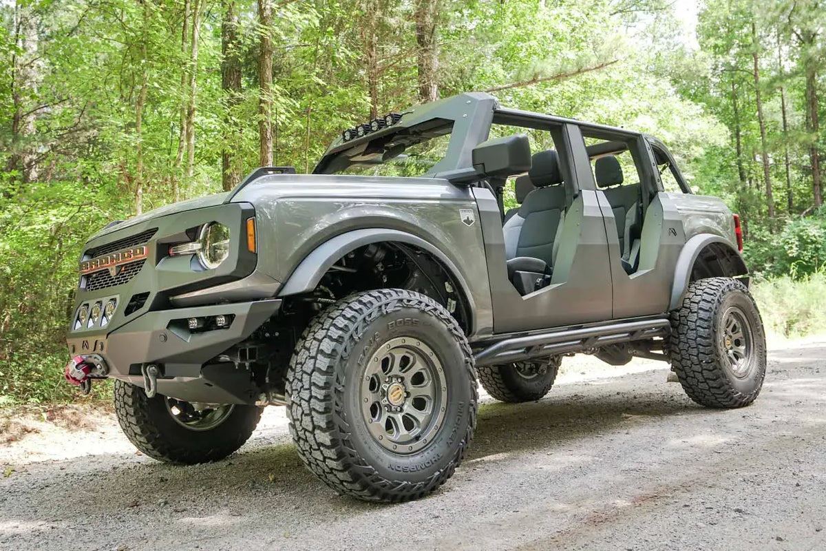 Fab Fours Trail Doors on a lifted gray Ford Bronco outdoors, front driver-side view, with the open steel doors, winch bumper and roof-mounted lights