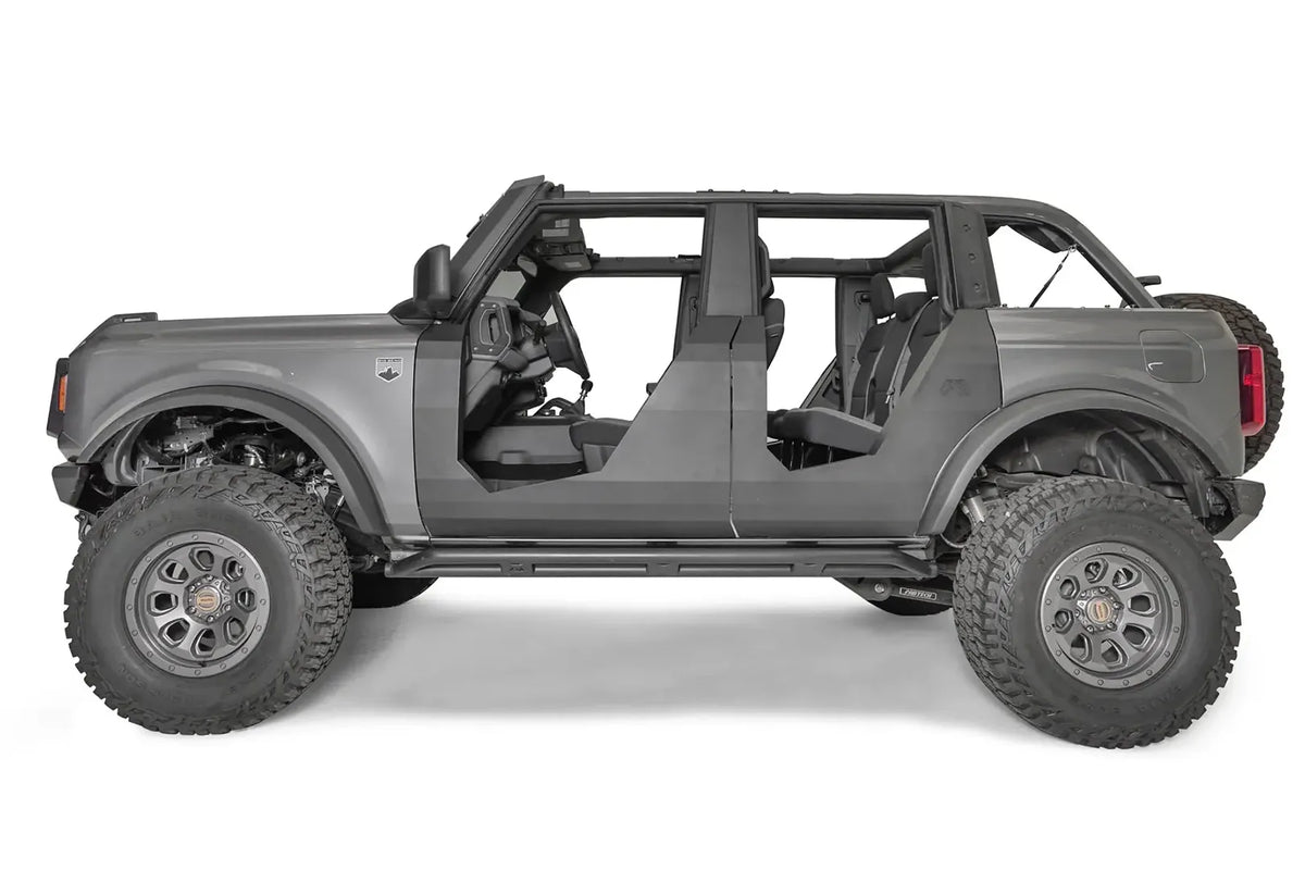 Fab Fours Trail Doors on a lifted gray four-door Ford Bronco, driver-side profile, showing the clean matte black steel doors with open upper sections and Fab Fours logo