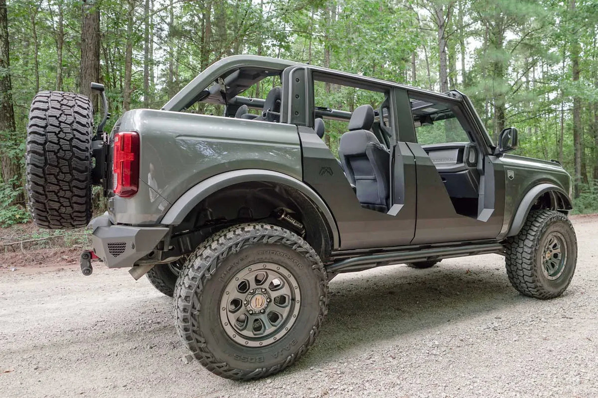 Interior view of a Fab Fours Trail Door on a Ford Bronco passenger side, showing the low steel door frame and open outside view beside the dashboard