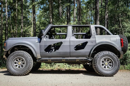 Fab Fours Trail Door Inserts on a lifted gray four-door Ford Bronco outdoors, driver-side profile, with the angular steel door inserts and Fab Fours logo on the rear door