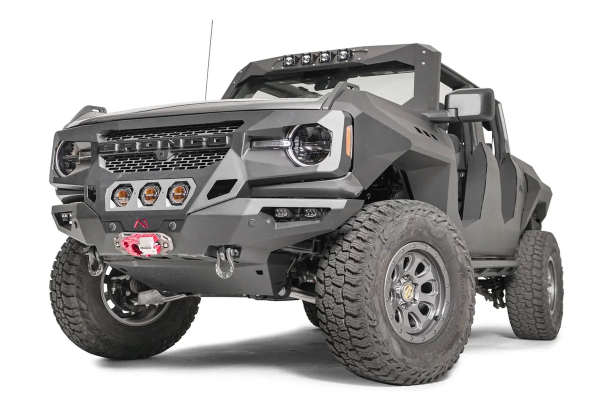 Fab Fours front steel fenders on a lifted gray Ford Bronco, driver-side front three-quarter view, with Fab Fours winch bumper and amber pod lights