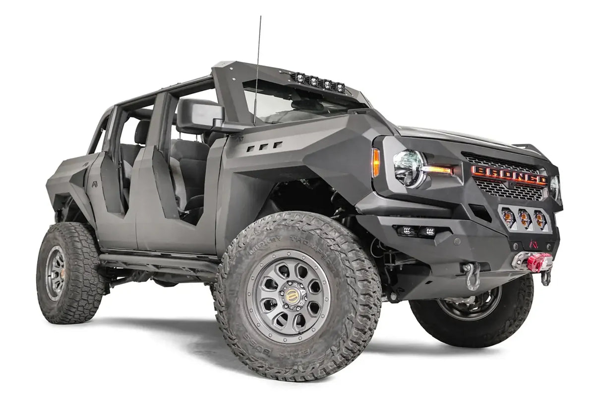 Fab Fours front steel fenders on a lifted gray Ford Bronco with doors removed, low passenger-side front three-quarter view, with Fab Fours winch bumper