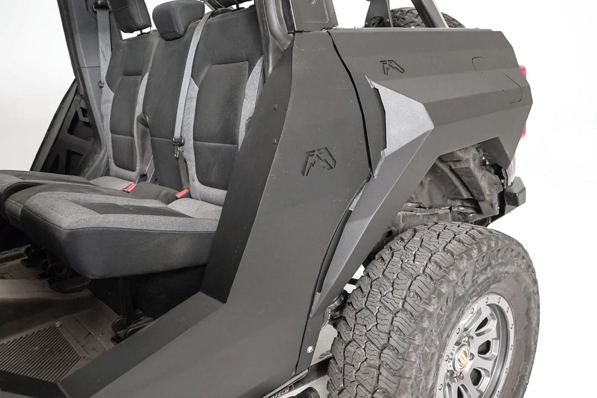 Close-up of Fab Fours rear steel fender with Fab Fours logos and body armor on the driver side of a gray Ford Bronco with doors removed