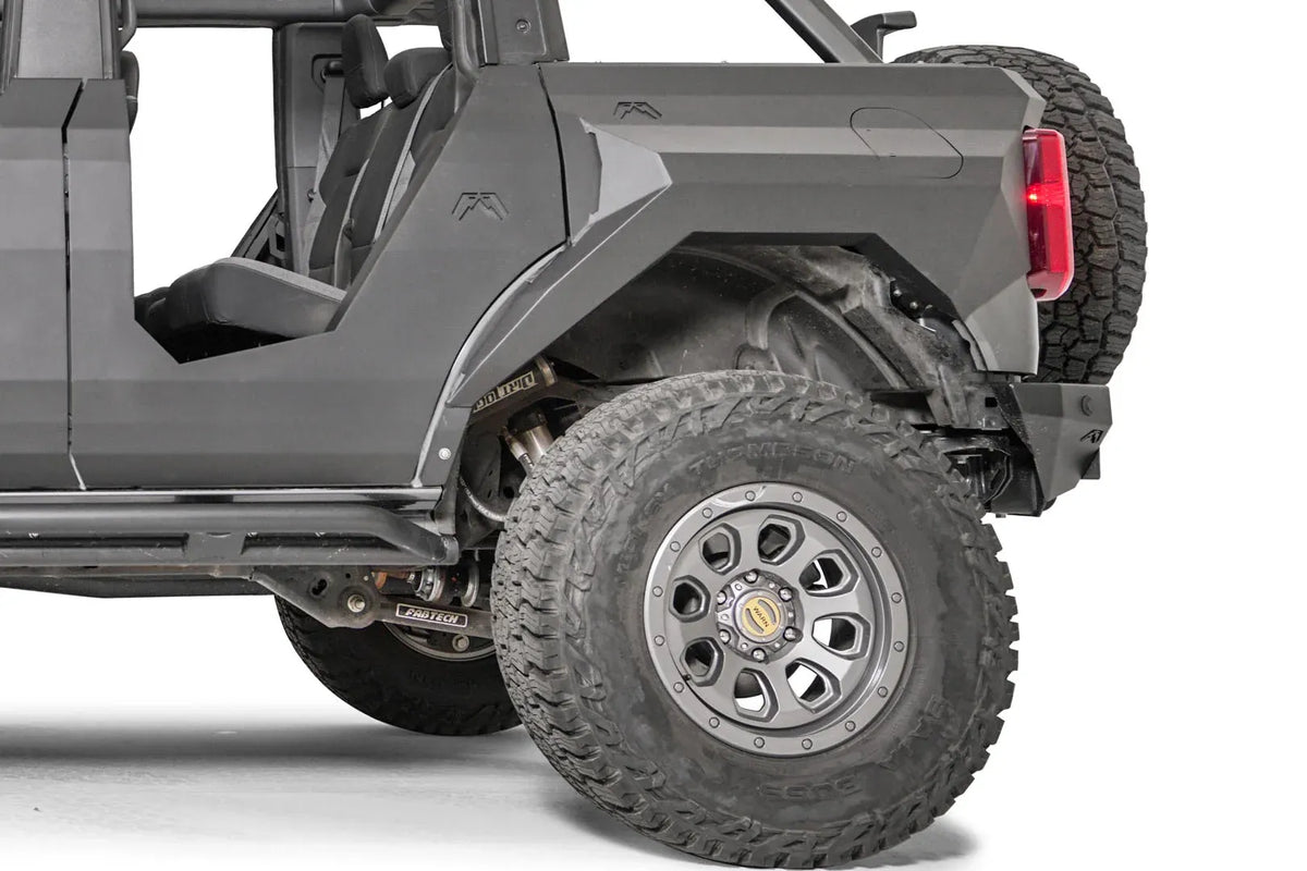 Fab Fours rear steel fender with integrated fuel door on a lifted gray Ford Bronco, driver-side view of the rear wheel