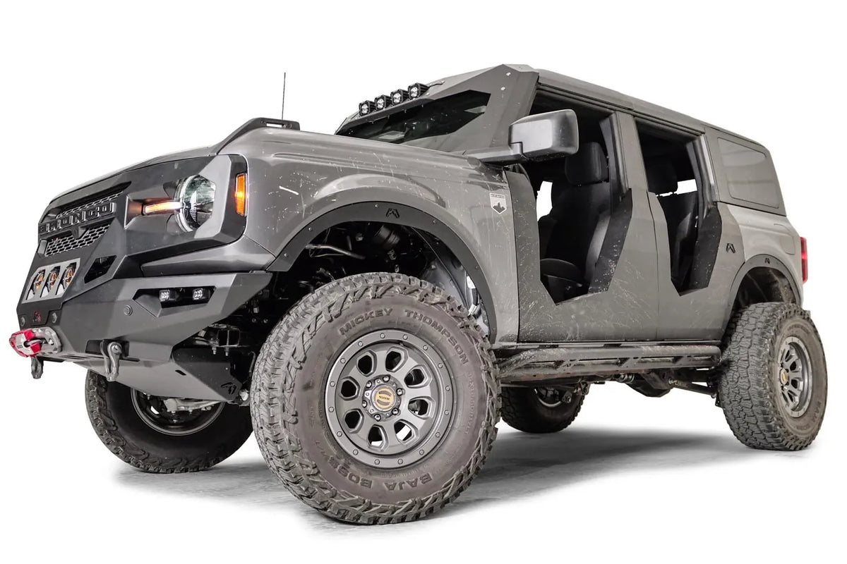 Fab Fours fender flares on a lifted gray Ford Bronco with doors removed, low driver-side front three-quarter view, with Fab Fours front winch bumper