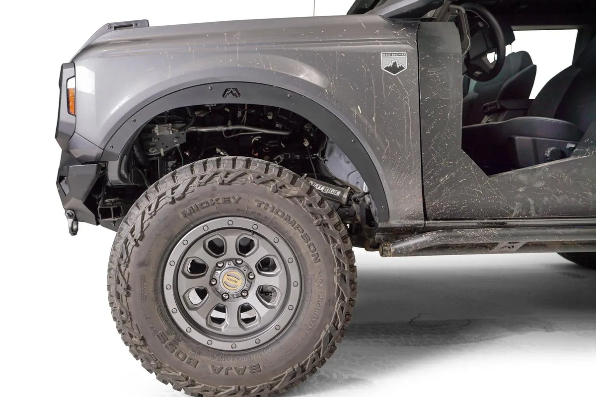 Close-up of Fab Fours front fender flare with Fab Fours logo on the driver side of a lifted gray Ford Bronco, with Mickey Thompson tire