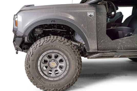 Close-up of Fab Fours front fender flare with Fab Fours logo on the driver side of a lifted gray Ford Bronco, with Mickey Thompson tire