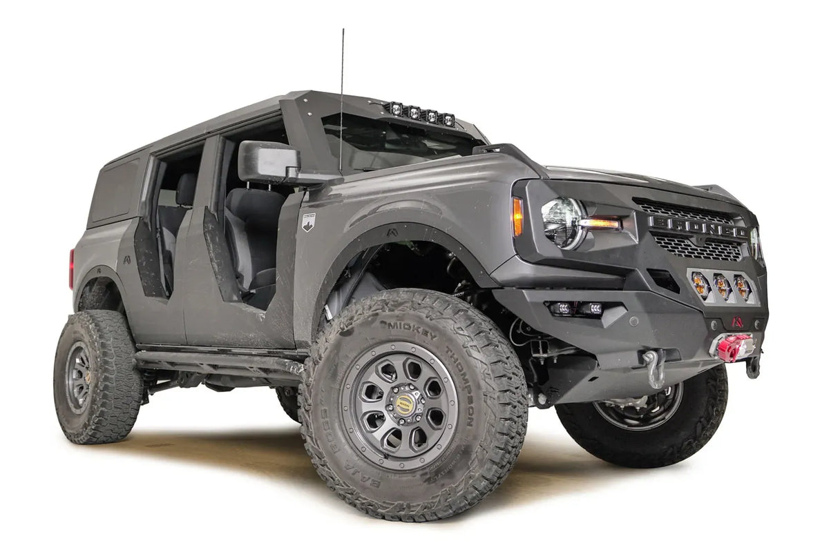 Fab Fours fender flares on a lifted gray Ford Bronco with doors removed, low passenger-side front three-quarter view, with Fab Fours front winch bumper