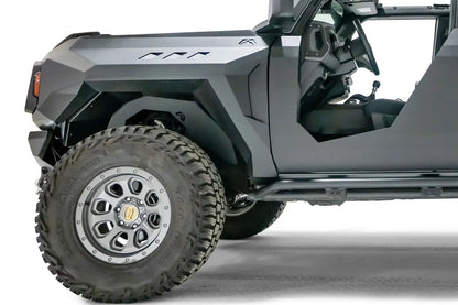 Fab Fours inner fender on a lifted gray Ford Bronco, front driver-side close-up, showing the black steel liner filling the front wheel well behind the tire under a Fab Fours fender