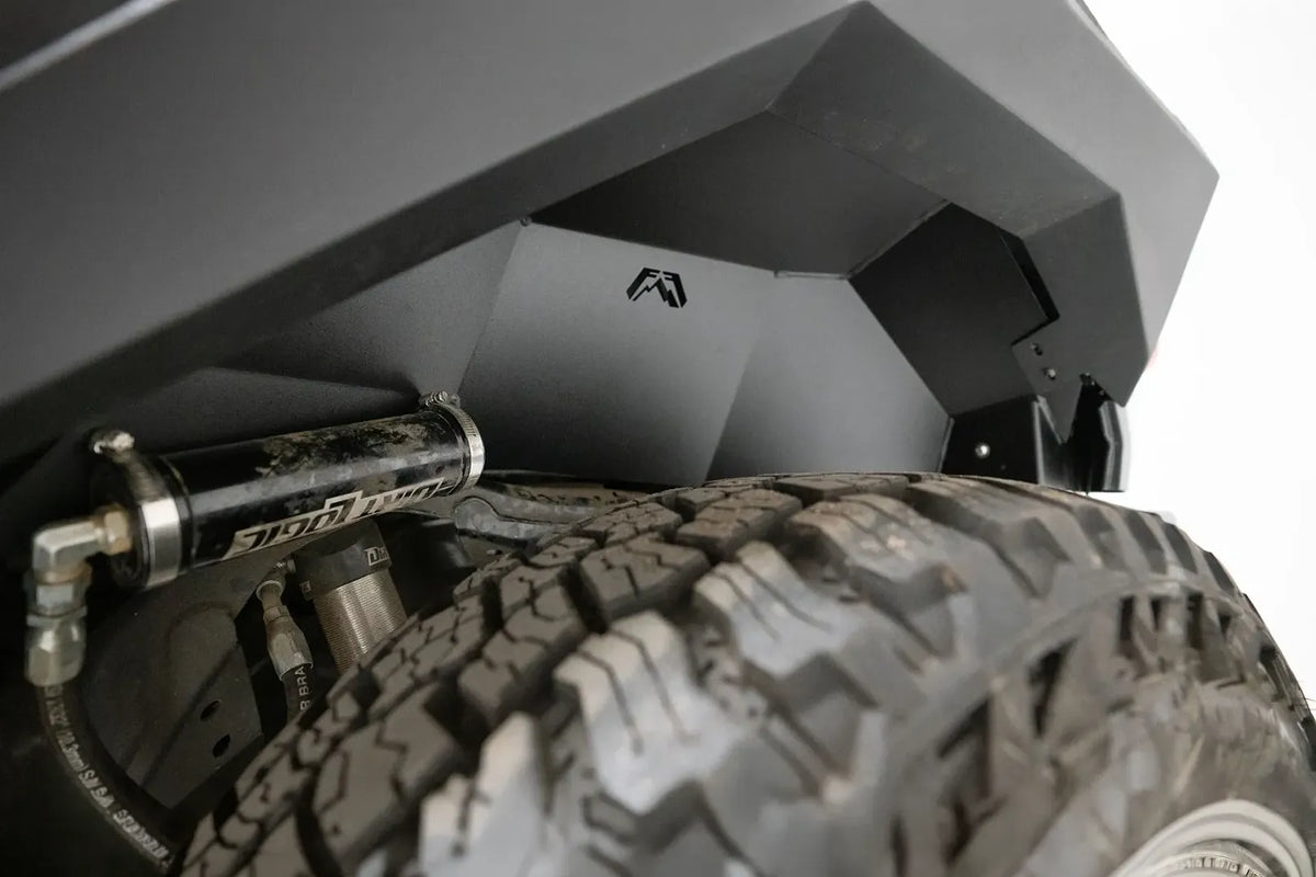 Close-up of Fab Fours rear inner fender liner with Fab Fours logo cutout above the tire and shock reservoir on a Ford Bronco