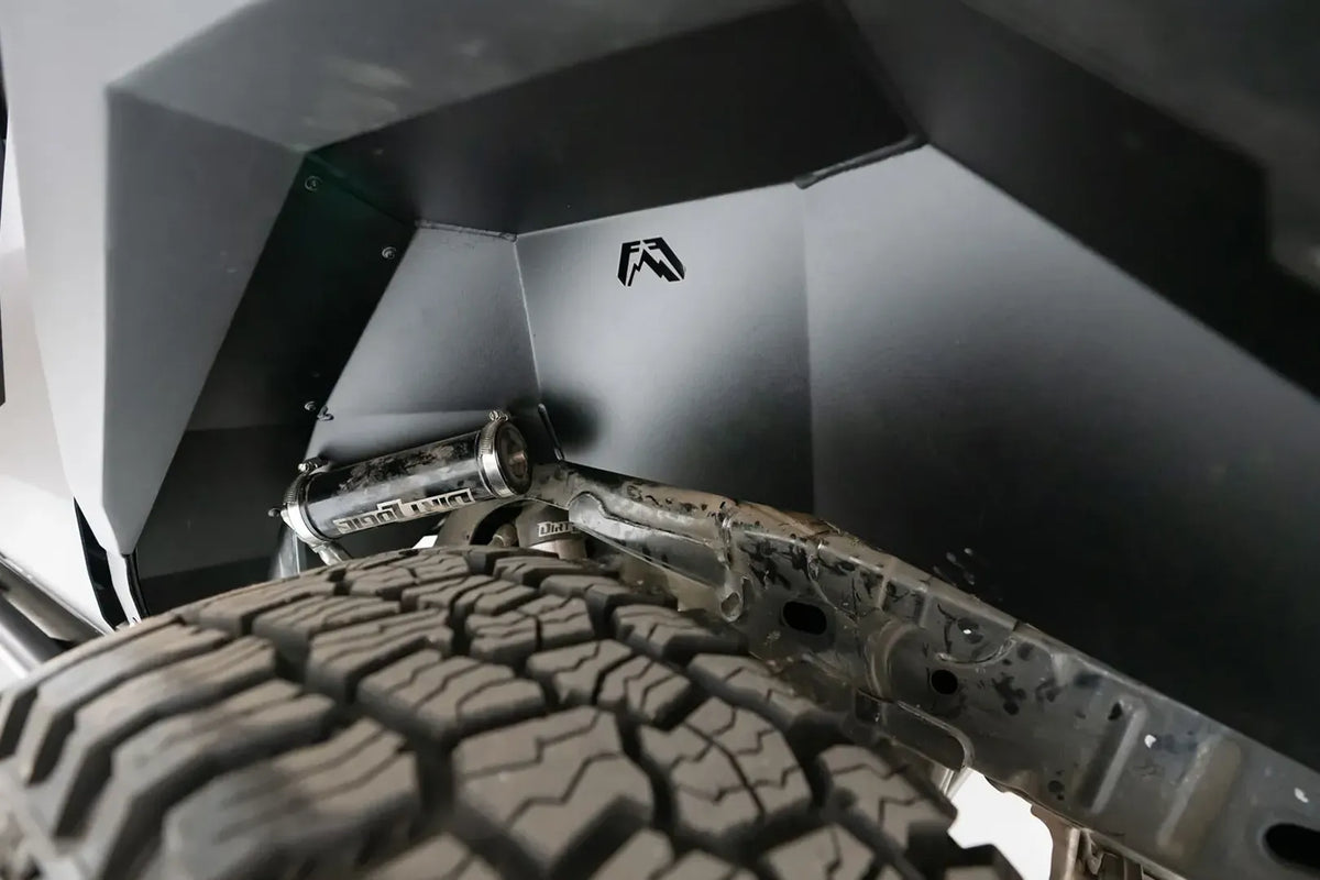 Close-up of Fab Fours inner fender liner with Fab Fours logo cutout inside the wheel well of a Ford Bronco, above the tire and suspension